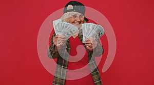 Rich pleased boss senior woman waving money dollar cash banknotes like a fan success business career