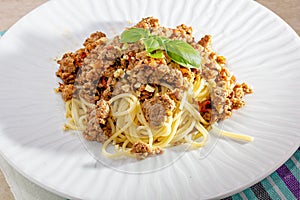 Rich spicy Italian spaghetti Bolognaise with parmesan cheese and a fresh green basil leaves viewed from overhead on a