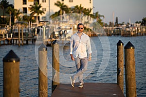 Rich summer business man near the yacht. Portrait of fashion male model outdoor. Fashion male posing near yachts. Man in