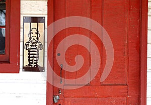 Mr. Monopoly Man shown wearing a jail uniform by a locked red door.