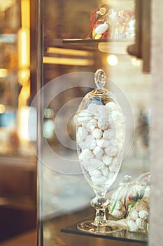 Rich variety of white chocolates, candies in glass jars in display window of typical italian pastry shop