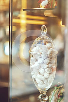 Rich variety of white chocolates, candies in glass jars in display window of typical italian pastry shop