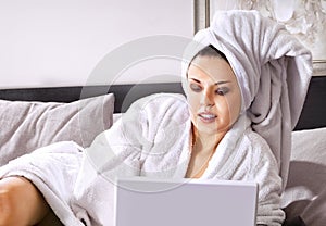Rich woman with laptop on bed