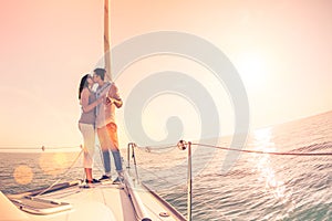 Rich young couple in love on sailboat cheering at sunset