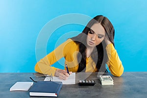 A rich young girl counts money at home at her desk for her next major financial investment