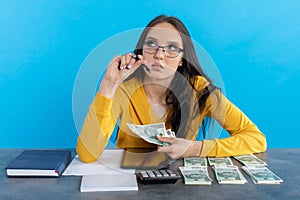 A rich young girl counts money at home at her desk for her next major financial investment