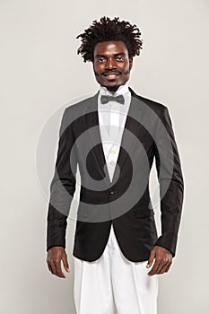 Richly african gentelman in tuxedo and bow of tie smiling
