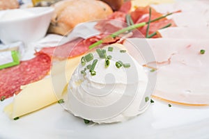 Richly covered breakfast table with ham and cheese with chives on it