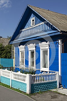 Richly decorated ornamental carved windows, frames on vintage blue wooden rural house. Countryside in Belarus