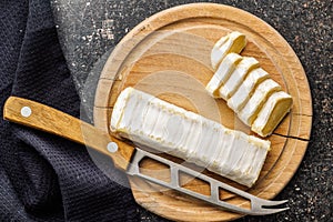 Cheese on wooden board with cloth and knife