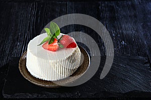 Ricotta with strawberries and basil leaves on a black stone board. Copy space