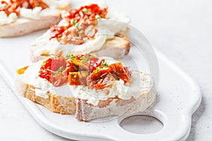 Ricotta and sun dried tomatoes sandwiches on white board