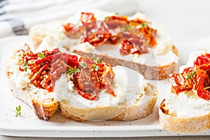 Ricotta and sun dried tomatoes sandwiches on white board