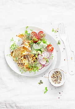 Ricotta zucchini fritters and fresh vegetables salad. Cucumbers, cherry tomatoes, radishes, micro greens and zucchini pancakes on