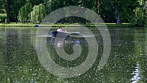 ride a boat in the summer on a pond in the park, a young man rows on oars High quality FullHD footage