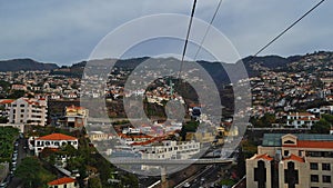 Ride in the cable car in Funchal, Madeira, Portugal with view over the city with highway, buildings and mountains.