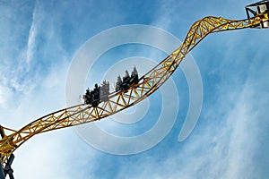 Ride roller coaster in motion in amusement park on blue sky background