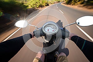 Rider driving scooter on an asphalt road. Motion blurred backgro