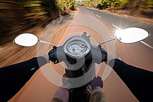 Rider driving scooter on an asphalt road. Motion blurred backgro