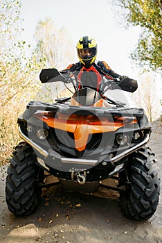 Rider in helmet on quad bike, front view, closeup