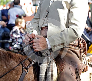 Rider on horseback dressed in traditional costume and holding glass of fino sherry manzanilla sherry at the April Fair