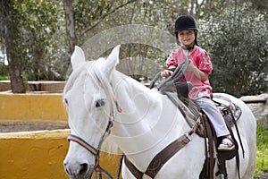 Rider little girl jockey hat white horse in park