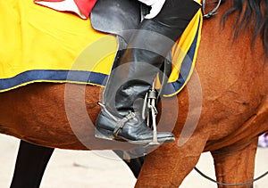rider& x27;s boot in a stirrup, sitting on a red horse in a yellow blanket. City Day celebration