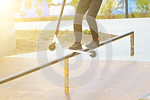rider on stunt kick scooter slides along edge of metal ramp in skate park