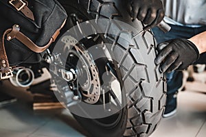 Rider use a tire plug kit and trying to fix a hole in tire`s sidewall ,Repair a motorcycle flat tire in the garage. motorcycle photo