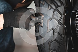 Rider use a tire plug kit and trying to fix a hole in tire`s sidewall ,Repair a motorcycle flat tire in the garage. motorcycle photo