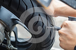 Rider use tire plug kit and trying to fix a hole in tire's sidewall ,Repair a motorcycle flat tire in the garage. motorcycle photo