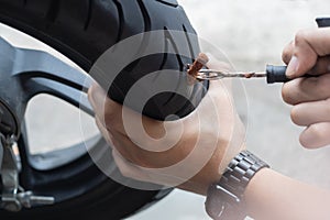 Rider use a tire plug kit and trying to fix a hole in tire sidewall ,Repair a motorcycle flat tire in the garage. motorcycle photo