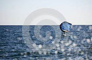 rider with wing foil sails through the sea and splash of water drops jump into the sea