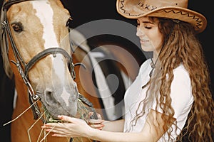 Portrait of rider woman feeding her brown horse