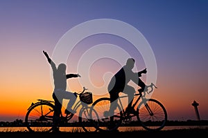 Riders cycling against sunset in silhouette with lots of negative space and dramatic sky