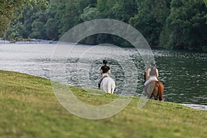 Riders, two young women riding horses down the river