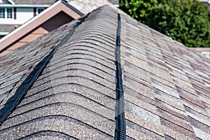 Ridge cap vent installed on a shingle roof for passive attic ventilation on a residential house.