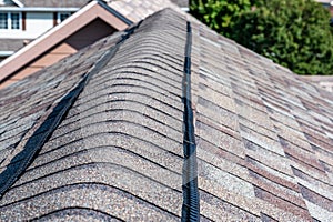 Ridge cap vent installed on a shingle roof for passive attic ventilation on a residential house. photo
