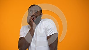 Ridiculous African-American man feeling fear isolated on yellow background