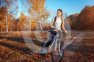 Riding bicycle in autumn forest. Young woman having rest after workout on bike enjoying nature. Healthy lifestyle