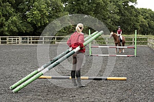 Riding school pupil and instructor with poles for a jump