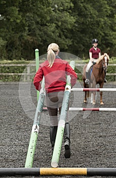 Riding school pupil and instructor with poles for a jump