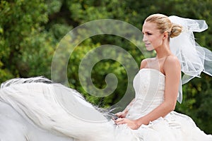 Riding to meet her white knight on the special day. A gorgeous young bride riding a white horse on her wedding day.