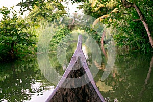 Riding wood fishing boat in kerala backwaters village water channel under palm trees, a pristine natural environment during