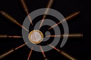 Rifle ammo around one euro coin on black background. Symbolizes the war for money and one of the world`s problems