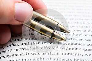 Rifle bullet model in hand on a old book page