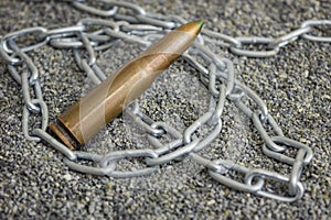 An rifle cartridge and an iron chain are thrown on the ground