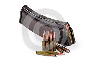 Rifle cartridges against the assault rifle magazine on white background