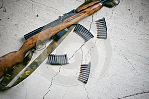 Rifle with cartridges on a textured concrete slab