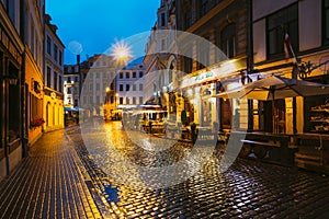 Riga, Latvia. Lido Cafe In Lighting At Evening Or Night Illumination In Old Town In Tirgonu Street